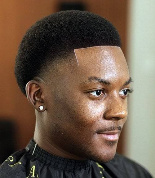 Young Black man showcasing a professional afro taper fade with a sharp, straight lineup.